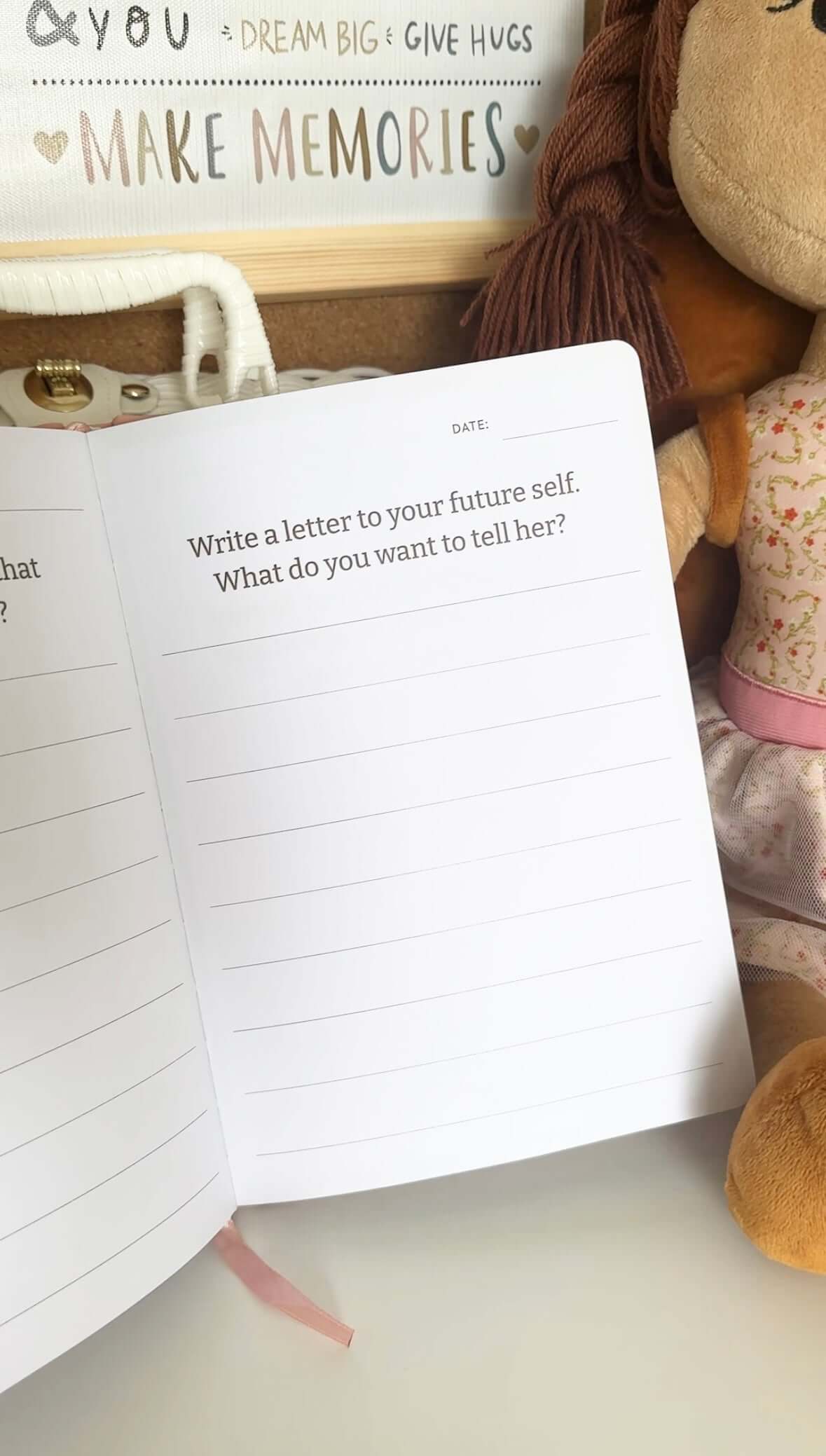 Open journal page with prompt asking to write a letter to your future self, featuring doll beside it.