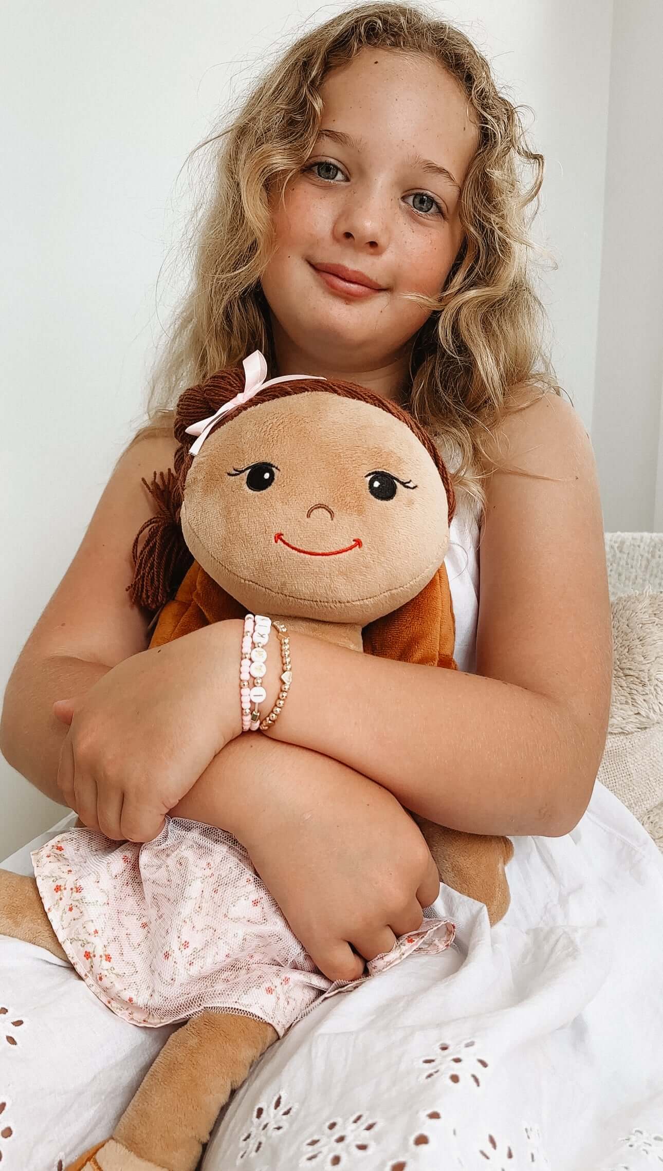 Girl hugging a plush doll with brown hair, promoting self-worth through journaling and play.