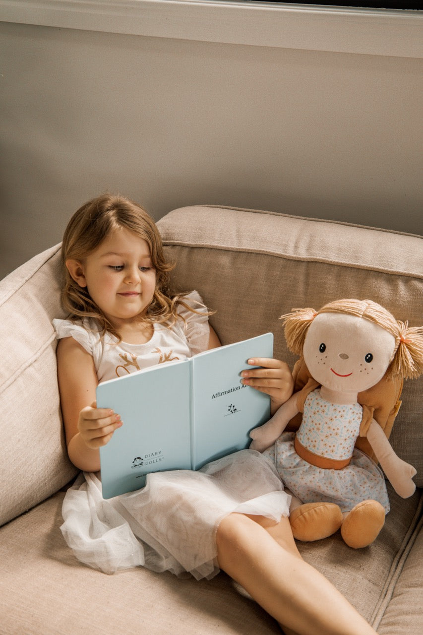 Girl reading her Affirmation Alice journal with Alice beside her