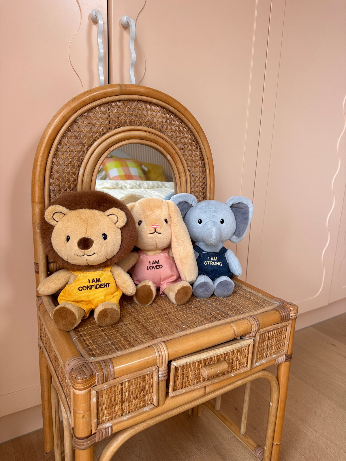 Levi Lion, Bella Bunny and Eli Elephant Affirmation Friends sitting together on a rattan chair