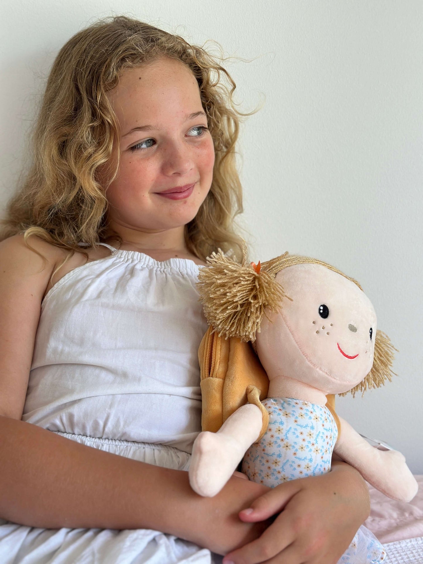 Smiling girl cuddling 'Affirmation Alice' doll, promoting self-worth and confidence in children.