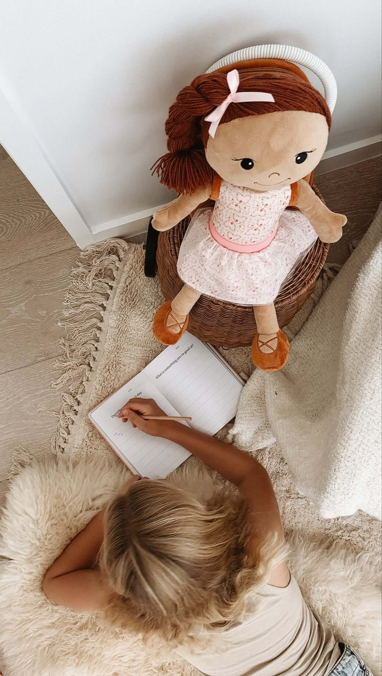 A girl journaling beside Journal Jasmine doll, promoting self-expression and confidence through creativity.